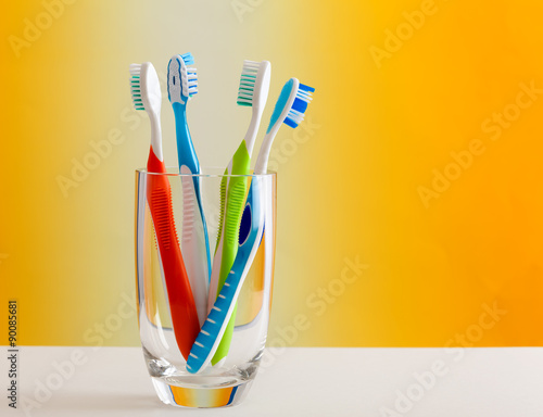 Glass holding colorful toothbrushes