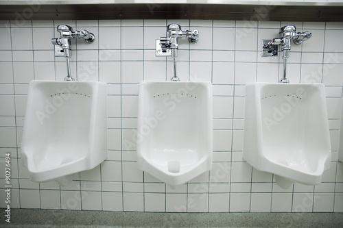 Three white urinals in men's bathroom