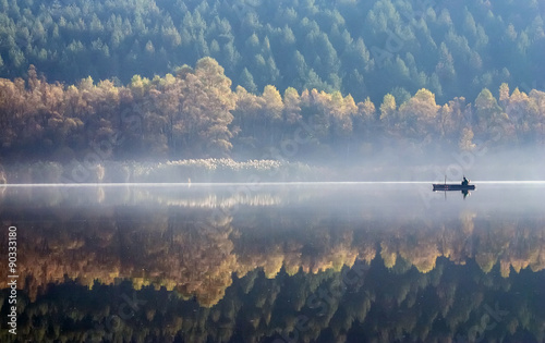 One angler fishing on a misty lake.