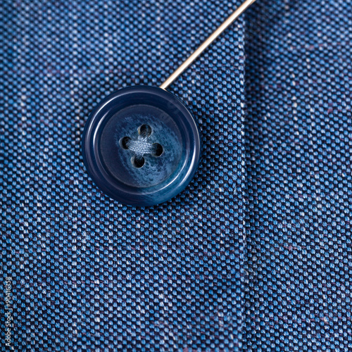 attaching of button to blue silk cloth by needle