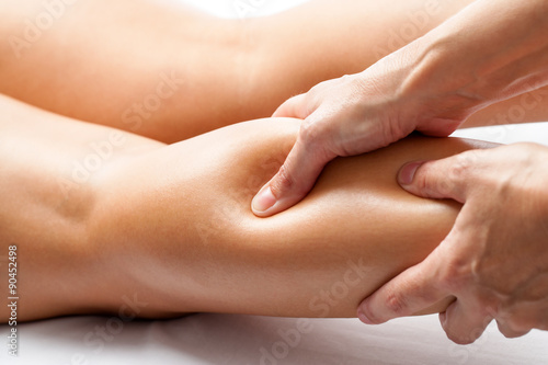 Therapist applying pressure with thumb on female calf muscle.
