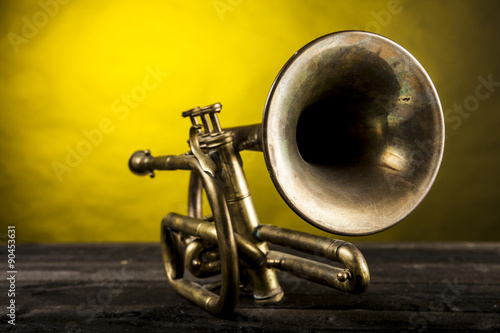 Tromba in ottone su piano di legno e sfondo color oro