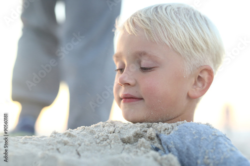 Dziecko na plaży.Wesoły chłopiec bawi się w piasku na plaży