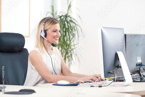 Portrait of smiling young woman working on a computer in a call center