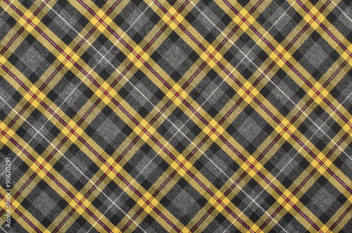 Scottish tartan pattern. Yellow with grey and black plaid print as background. Symmetric rhombus pattern.