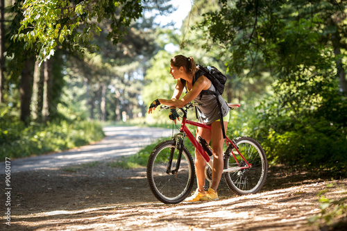 Pausing her mountain bike ride, female takes a break, admiring the natural beauty surrounding her in the forest.