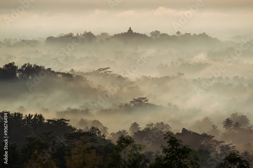 Colorful sunrise over Borobudur temple in misty jungle forest, I