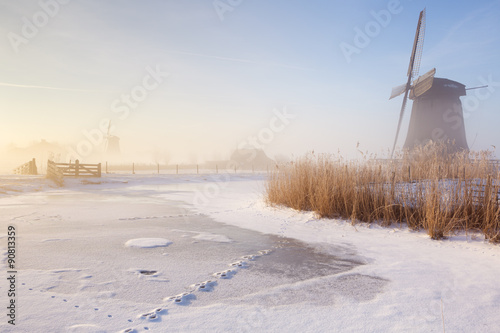 Dutch windmills in a foggy winter landscape in the morning