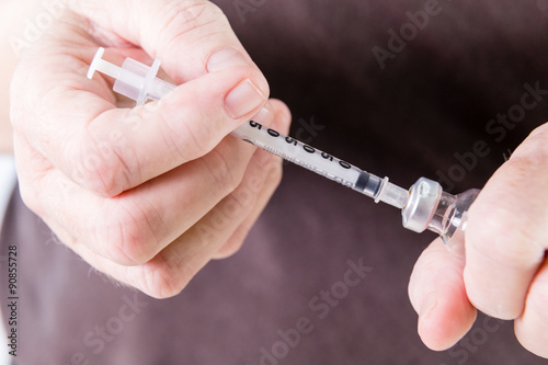 Syringe drawing insulin from vial