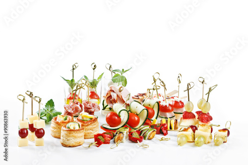 great attractive set of canapes with vegetables, cheese, fruits, berries, salami, seafood, meat and decoration on white background studio isolated with space for text template