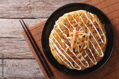 Japanese okonomiyaki on a wooden table. Horizontal top view 