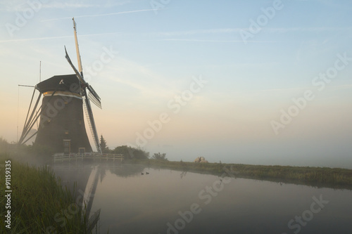 Foggy windmills on a dike