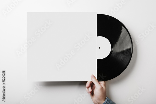 Hand holding vinyl music album template on white wall background