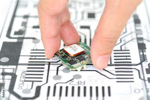 Closeup hand picking electronics device on schematics background