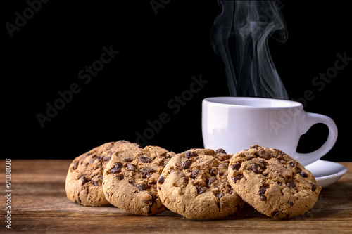 steaming cup of coffee with chocolate cookies on wood