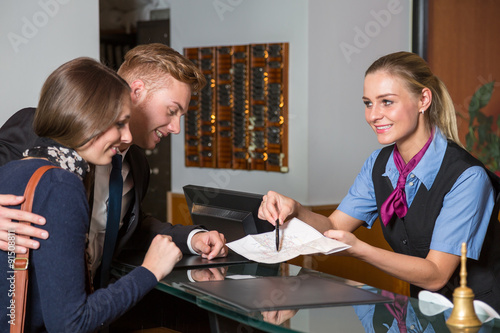 receptionist at hotel showing guest something on map