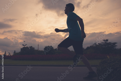 Runner athlete silhouette running in public park. man fitness sunrise jogging workout wellness concept.