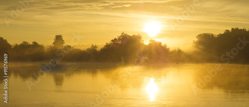 Wędkarz na łodzi łowiący w mglisty poranek nad rzeką