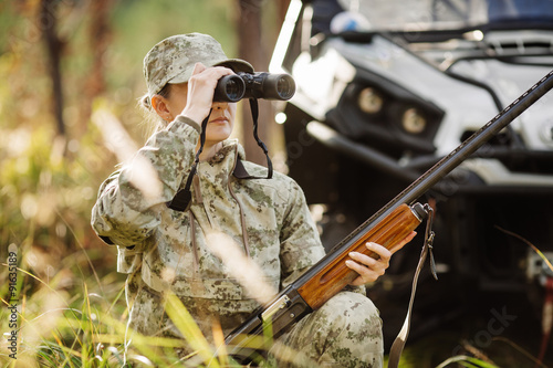 hunter with shotgun looking through binoculars in forest