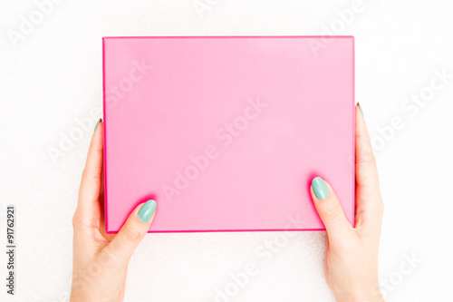 A female hands hold a empty(blank) pink box on the desk(table) top view
