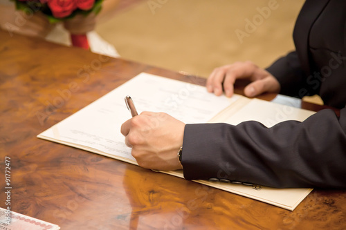 Bridegroom puts his signature to the document Certificate of Mar