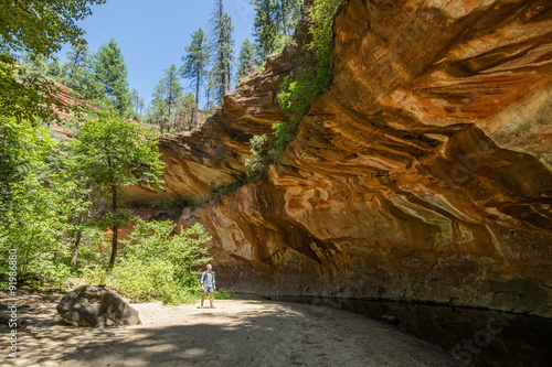 Man hiking through Oak Creek Canyon on the West fork trail surrounded by beautiful red rocks whilst on an outdoor adventure