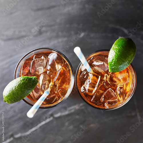 two glasses of iced tea on slate surface with retro straws and limes shot top down overhead