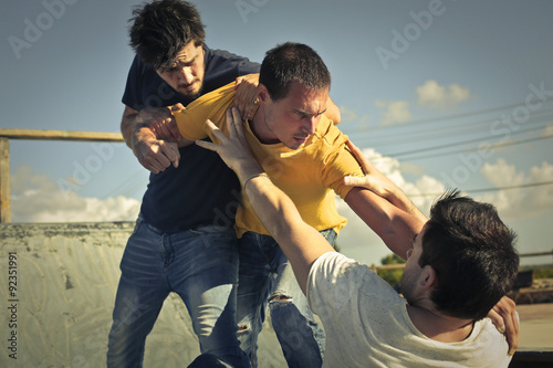Three young guys in a fight