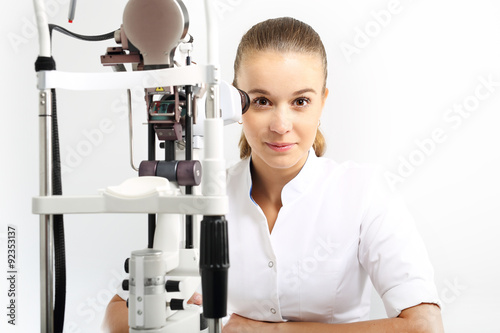 Szpital oddział okulistyki, młoda okulistka siedzi przy maszynie do badania oczu