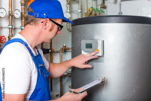 Handwerker kontrolliert im Heizungskeller den Heizungskessel oder Warmwasser Tank