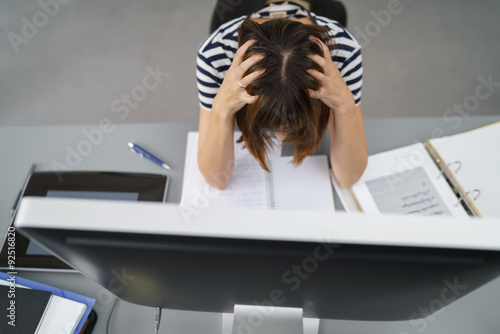 verzweifelte frau rauft sich die haare vor dem computer