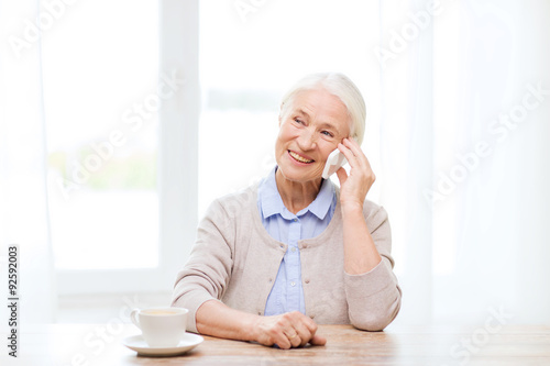 senior woman with smartphone calling at home