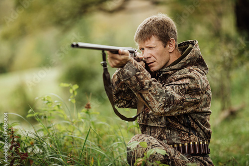 hunter in camouflage clothes ready to hunt with hunting rifle