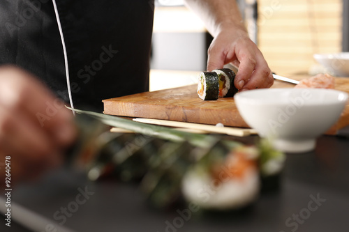Restauracja japońska, sushi. Sushi z łososiem, krewetką i ogórkiem przygotowywane przez kucharza