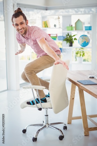Happy businessman standing on chair in office