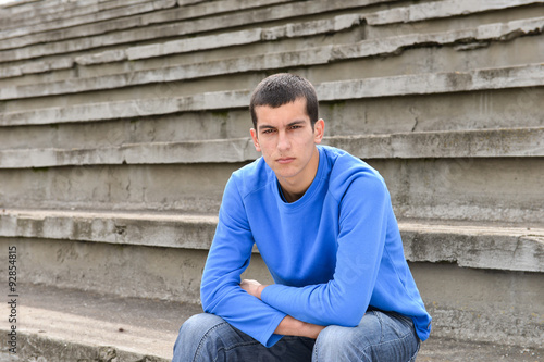 Teen boy sitting on stairs and looking at the camera