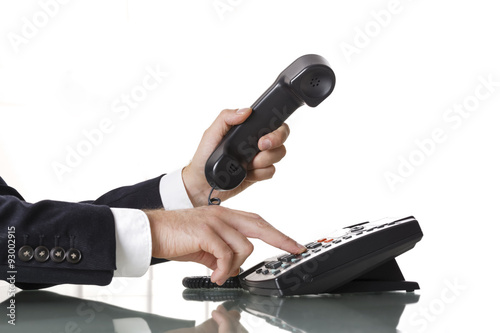 Close up of businessman hands dialing out on a black deskphone