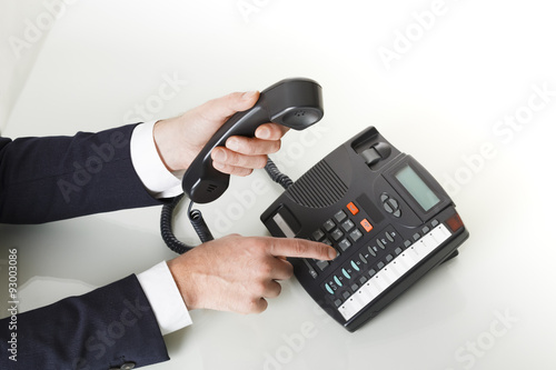 Top view of businessman hands dialing out on a black deskphone