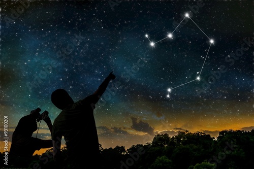 Libra constellation of zodiac on night sky. Astrology concept. Silhouettes of adult man and child observing night sky.