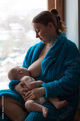 Woman breastfeeding her baby near a window, color image