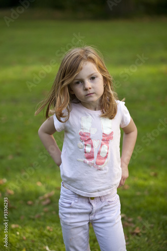 Young Ballerina. A rough and ready young girl, pulling her trousers up in an efficient manner has pretty ballerina feet on her t-shirt.