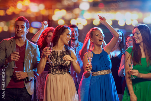 happy friends with champagne dancing at nightclub