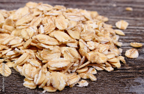 Heap of oat flakes on wooden background