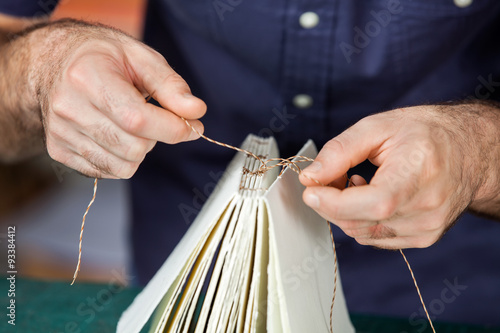 Midsection Of Male Worker Binding Pages