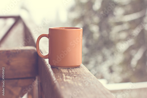 A cup with a hot drink on the background of the winter forest
