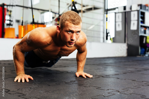 Young muscular athlete doing suspension pushups