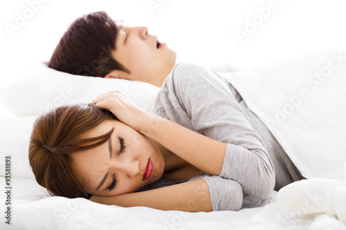 young Woman covering ears while husband is snoring