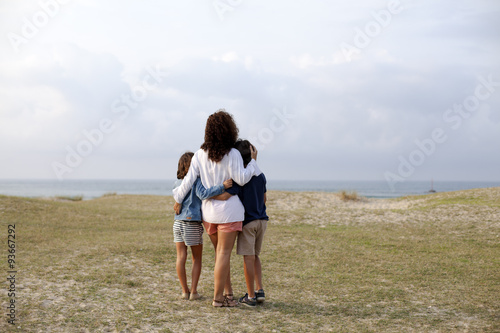 Madre e hijos abrazados mirando el mar