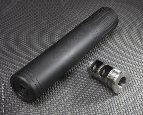 Silencer and the adapter to easily mount it on a gun seen on a rubber work mat.