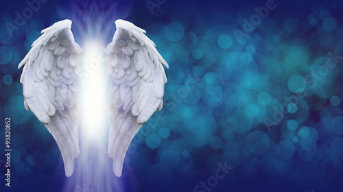 Angel Wings on Blue Bokeh Banner - Wide blue bokeh background with a large pair of Angel Wings on the left side and a shaft of bright light between